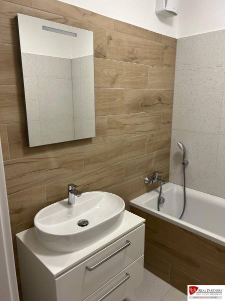 Fürdőszoba egy kétszobás lakásban, fa dekor padlóval és káddal.