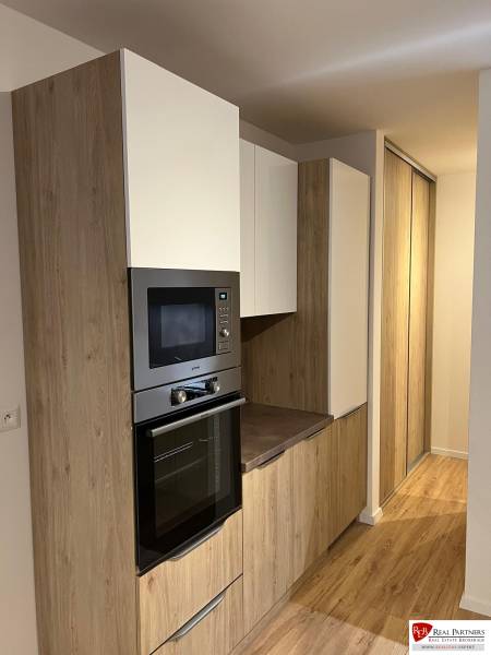 Kétszobás lakás konyhai része fa dekor padlóval és beépített szekrényekkel.