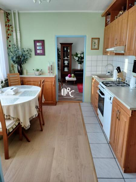 Konyha egy kétszobás lakásban fa dekorációjú padlóval és asztallal a szoba sarkában.