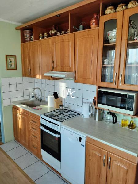 Konyha egy kétszobás lakásban fa szekrényekkel, tűzhellyel és háztartási gépekkel.