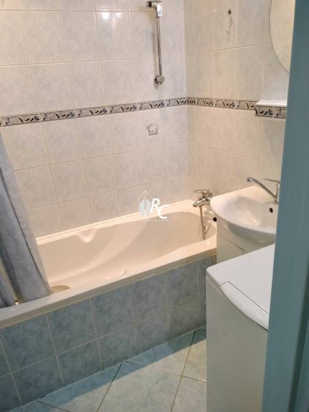 Fürdőszoba egy kétszobás lakásban káddal és világos csempékkel.