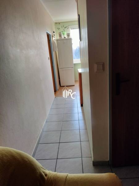 Folyosó hűtőszekrénnyel a kétszobás lakásban, csempe a padlón, világos falak.