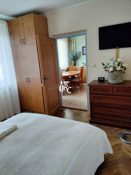 Hálószoba beépített szekrénnyel egy kétszobás lakásban, fa dekorációjú padlóval, az ajtó a konyhába vezet.