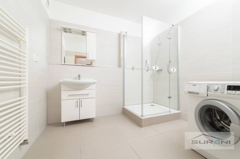 Fürdőszoba egy háromszobás lakásban mosdóval, zuhanyzóval és mosógéppel.