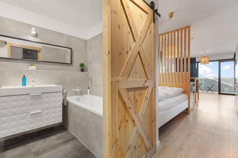 1 szobás lakás belső tere káddal és fa dekorációjú padlóval.