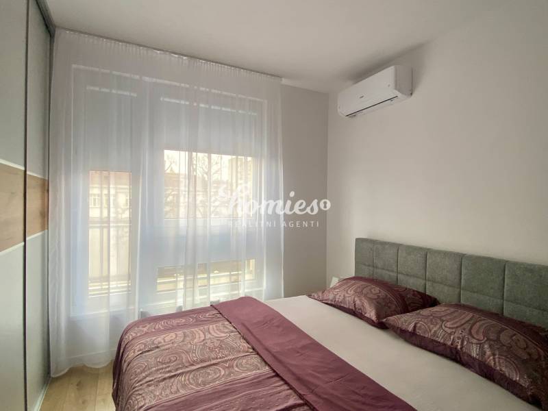 Hálószoba egy kétszobás lakásban légkondicionálóval és fa dekorációjú padlóval.