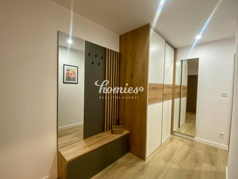 2 szobás lakás belső tere fa dekor padlóval, fogasfallal és tükörrel.