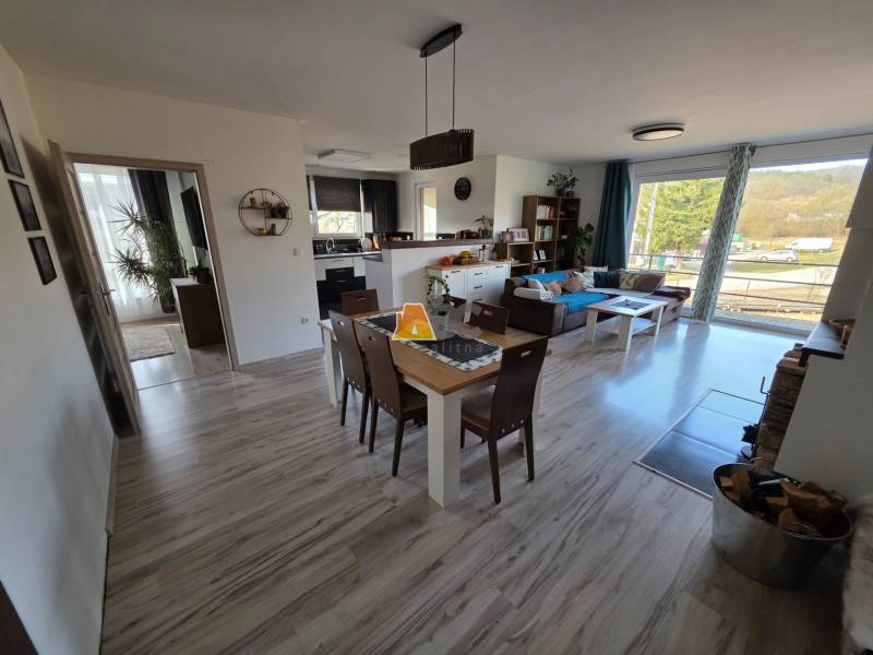 Nappali egy családi házban nyitott konyhával és fa dekorációjú padlóval.