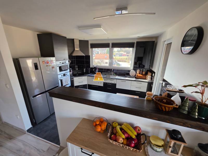 Konyha egy családi házban modern készülékekkel, pulttal és gyümölcsökkel az asztalon.