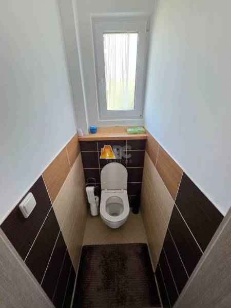Családi házban lévő WC ablakkal és kerámia csempékkel, dekor padlóval.