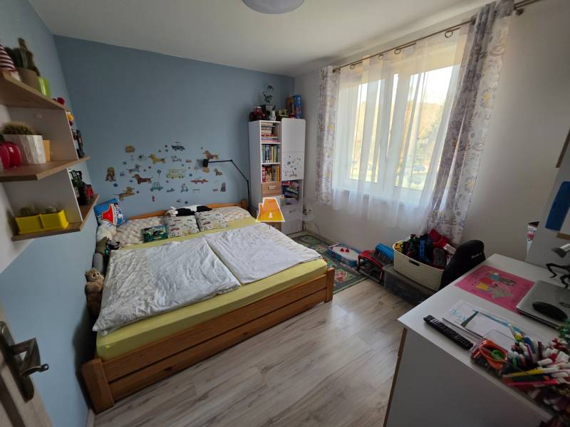 Gyerekszoba egy családi házban, fa dekorációs padlóval, ággyal és játékokkal.