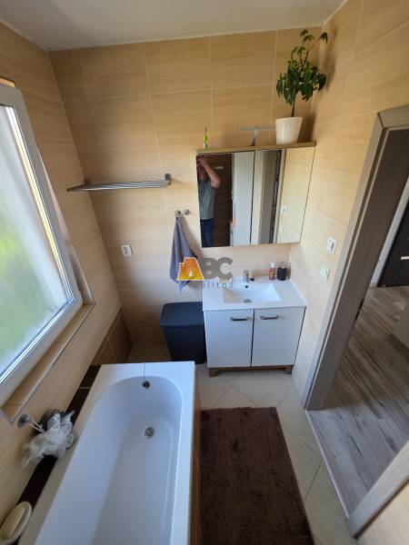 Fürdőszoba családi házban káddal, mosdó alatti szekrénnyel és világos ablakkal.