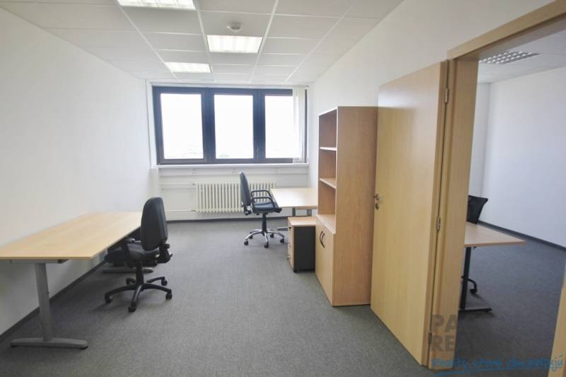 Irodák irodabútorokkal, szürke szőnyeggel és világos fallal, munkára készen.