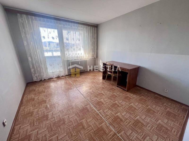 Szoba egy háromszobás lakásban, fa dekoros padlóval és nagy ablakokkal.