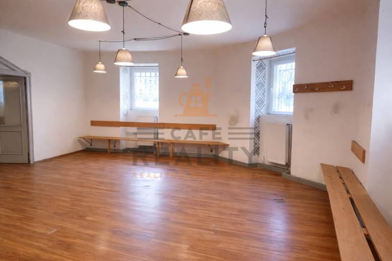 Kereskedelmi helyiség fa dekorációjú padlóval, padokkal és függő lámpákkal.