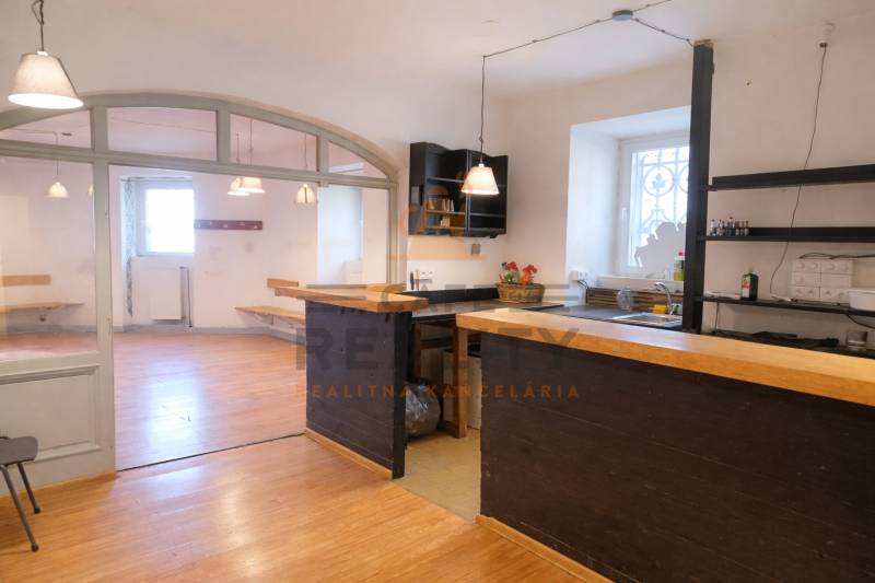 Üzlethelyiség bárpulttal és fa dekorációjú padlóval. Világos helyiség ablakokkal.