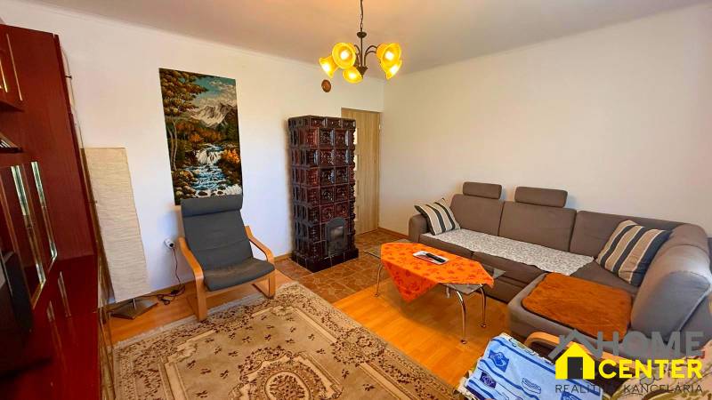 Nappali családi házban kanapéval, fotellel, cserépkályhával és természetképpel.