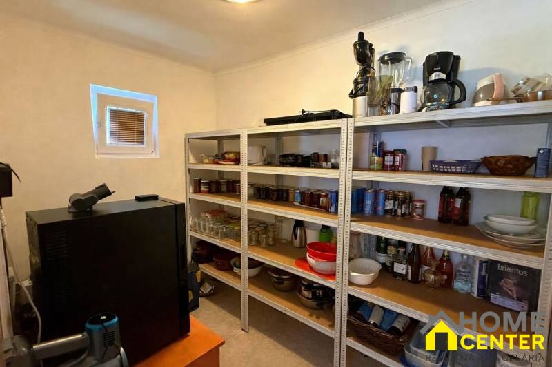 Családi ház kamrája polcokkal, tele készletekkel és konyhai eszközökkel.