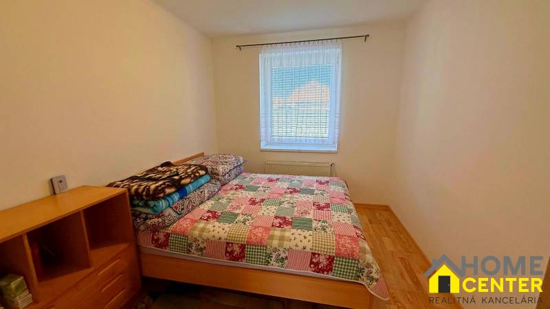 Hálószoba családi házban, ággyal és fa mintázatú padlóval.