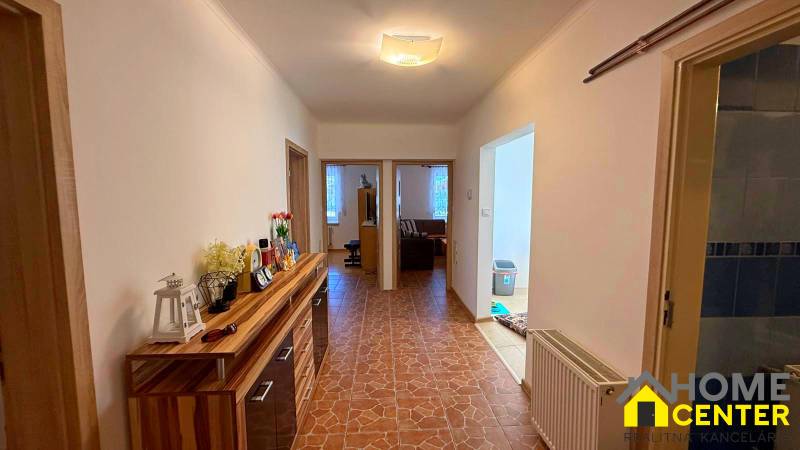 Folyosó a családi házban csempével és fa dekorációs szekrénnyel.