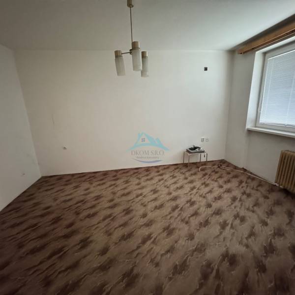 Szoba egy egyszobás lakásban fa dekorációjú padlóval és egyszerű világítással.