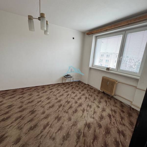 Egy szoba az egyszobás lakásban ablakkal, fehér falakkal és fa dekorációjú padlóval.