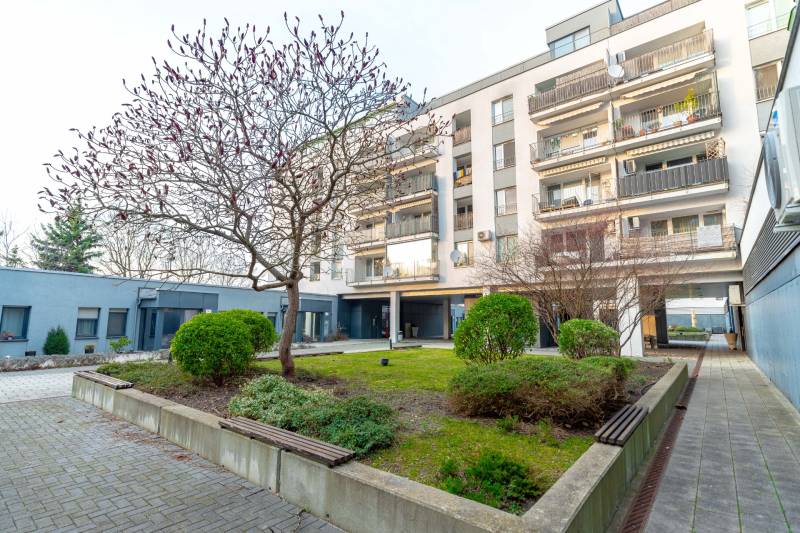 A Hrachova lakóház Pozsony-Ružinovban, zöldövezetben, fákkal és bokrokkal körülvéve.