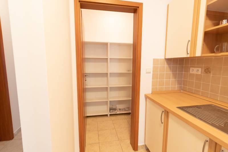 Konyha egy kétszobás lakásban polcokkal és csempével, fa dekoros szekrényekkel.