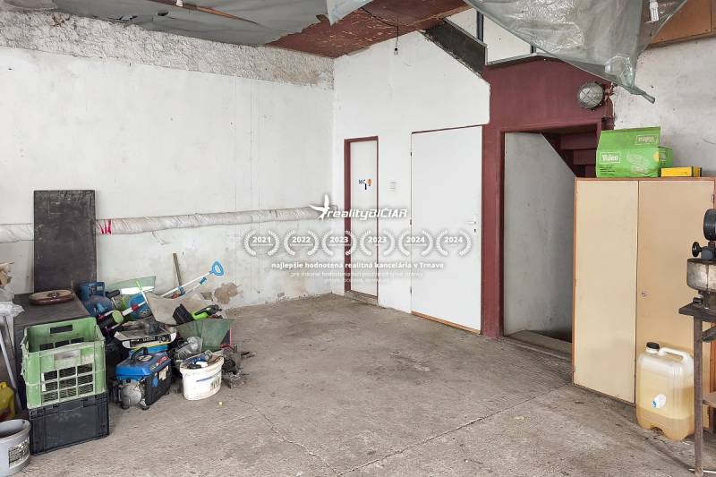 Családi ház garázs, elrakott szerszámok, betonpadló, lépcsők és fehér bútorok.