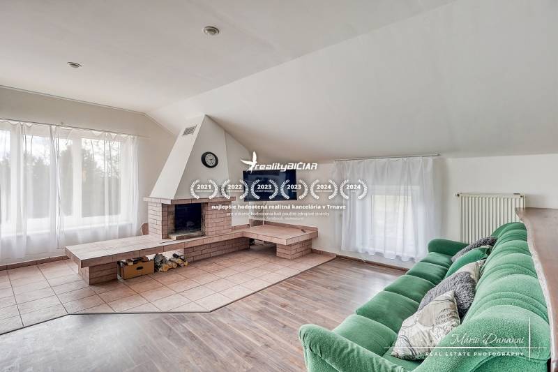 Nappali kandallóval, zöld kanapéval és fa dekorációjú padlóval egy családi házban.