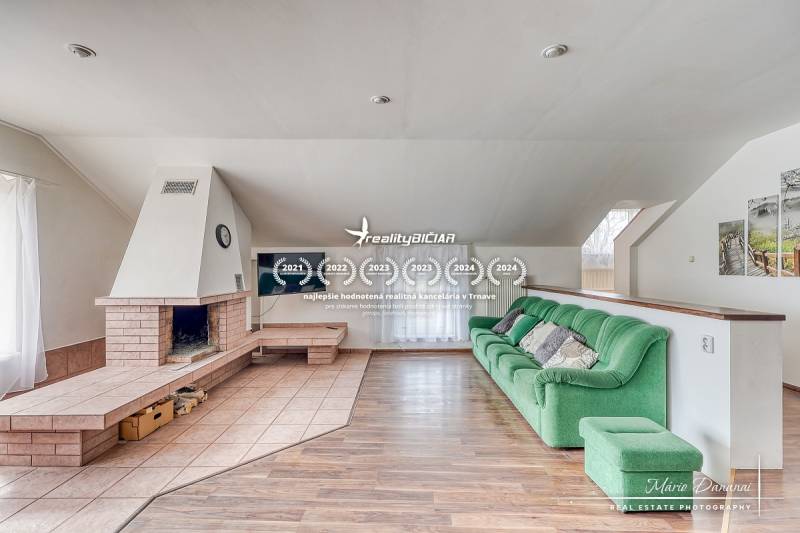 Nappali családi házban kandallóval, zöld kanapéval és fa dekoros padlóval.