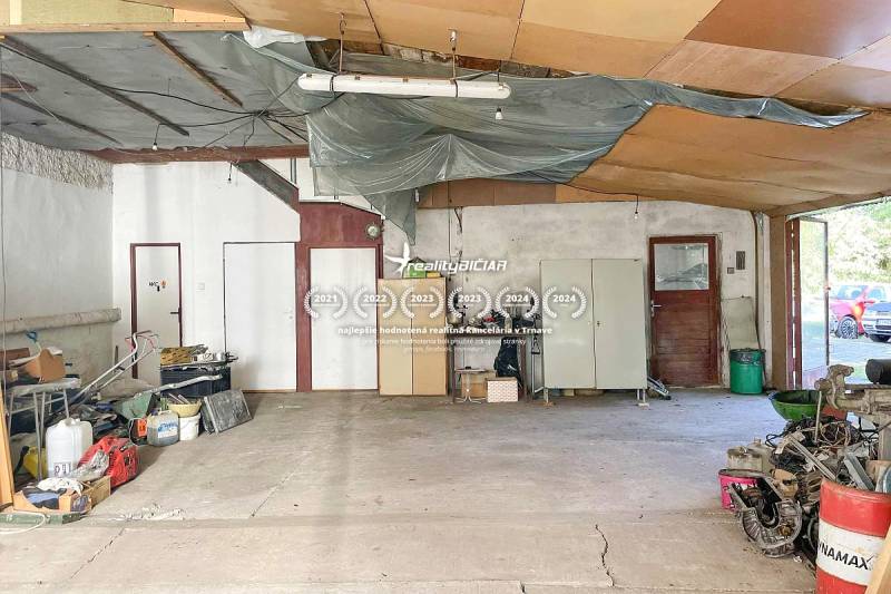 Családi ház belső tere tágas helyiséggel, elrakott dolgokkal és cementpadlóval.