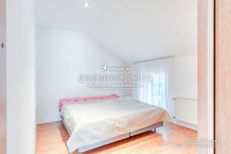 Hálószoba családi házban nagy ággyal és fa mintázatú padlóval.