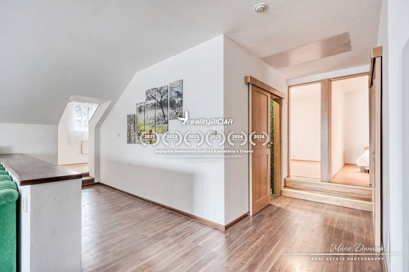 Családi ház belső tere lépcsőkkel, fa dekorációjú padlóval és képpel a falon.