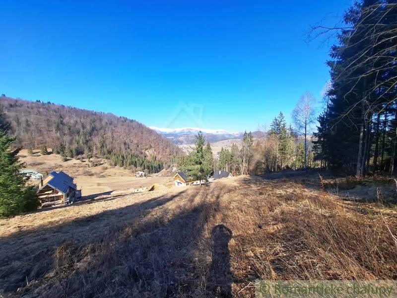 Táj Hronec községben, mezőgazdasági és erdőterületek hegyekre és házakra néző kilátással.