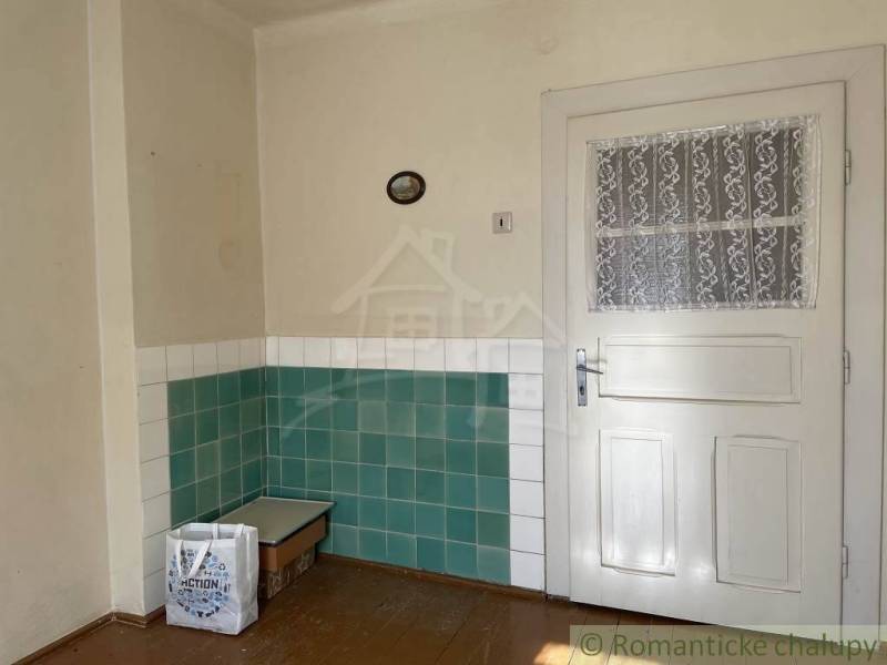 Családi ház belső tere fehér ajtókkal és zöld-fehér csempékkel a falakon.