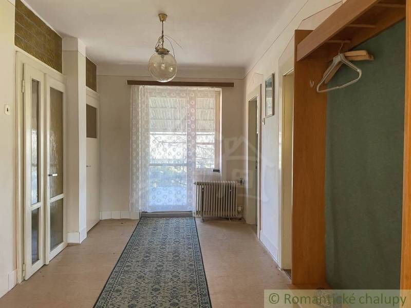 Családi ház belső tere fa dekorációjú padlóval, függönnyel és szőnyeggel.