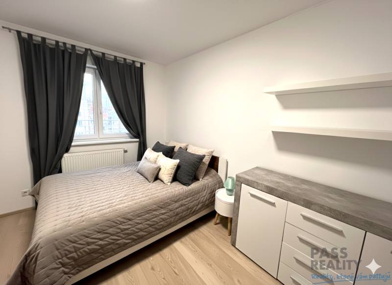 Hálószoba egy kétszobás lakásban ággyal, komóddal és függönyökkel, fa dekoros padlóval.