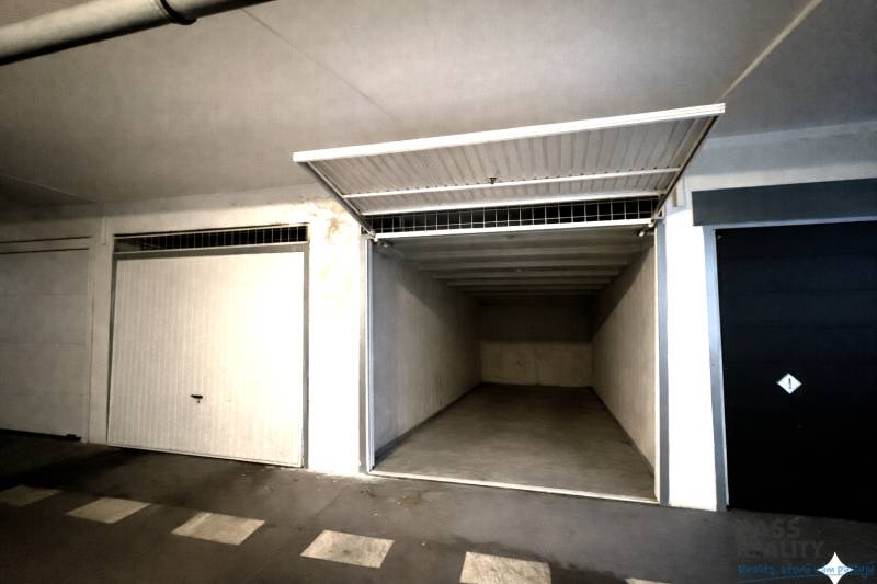 Nyitott garázs üres belső térrel és fehér falakkal.