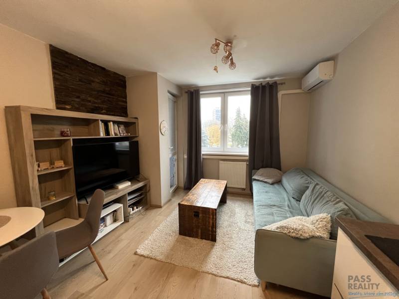 Nappali szoba fa mintás padlóval, kanapéval és televízióval egy kétszobás lakásban.