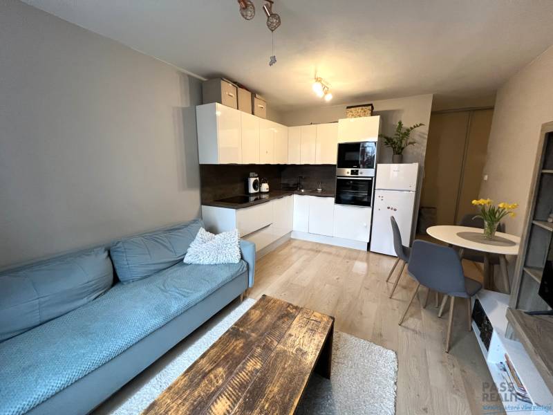 Obývací rész egy kétszobás lakásban konyhával, kanapéval és étkezőasztallal.