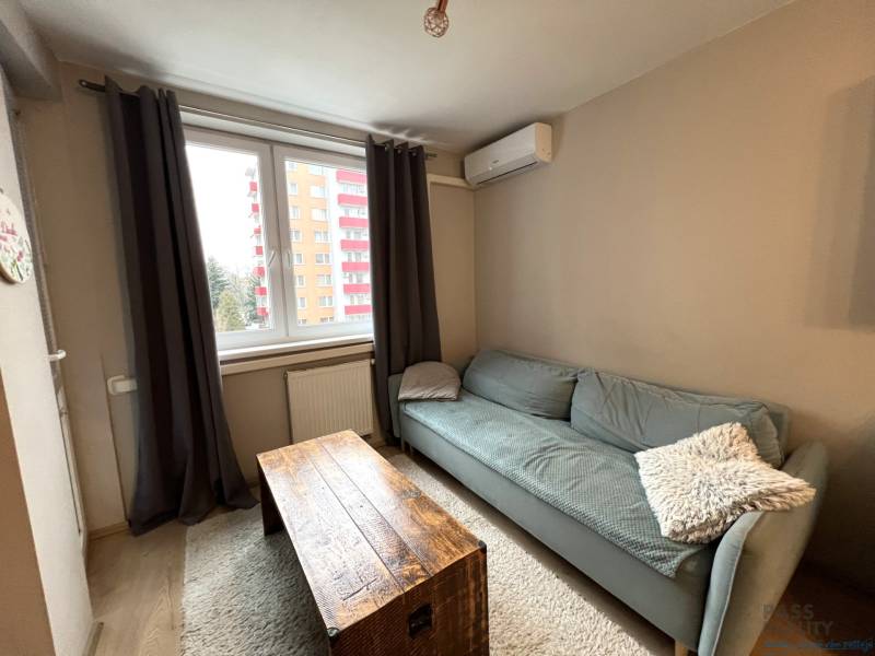 Nappali egy kétszobás lakásban, fa dekorációjú padlóval és kanapéval.