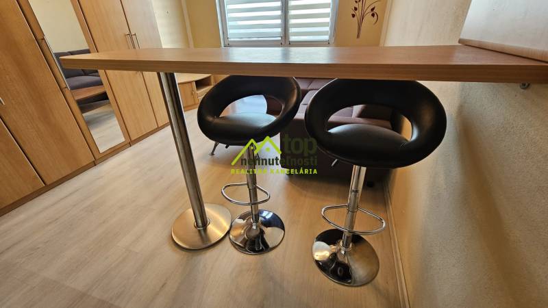 Stúdiólakás pulttal, székekkel és fa dekorációjú padlóval.