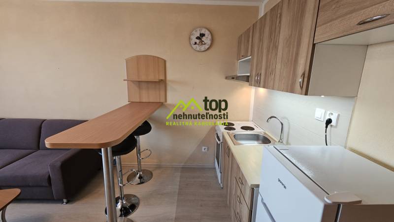 Kompakt garzonlakás konyhával, bárpulttal és kanapéval, fa dekorációjú padlóval.