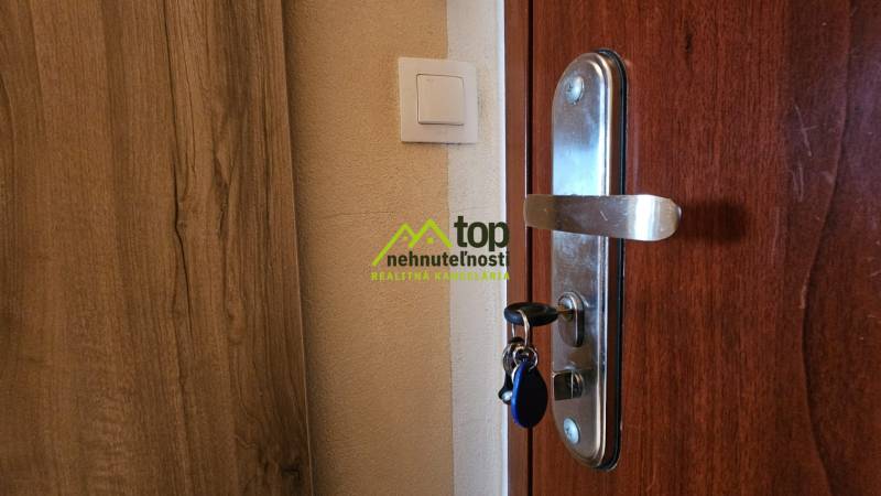 Faajtó a garzonlakásban fém kilinccsel és világos kapcsolóval.