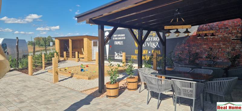 Kültér Újfaluban vendéglátóhelyiségekkel, terasszal és játszótérrel.