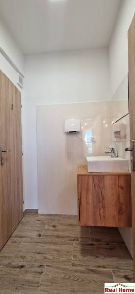 Egy vendéglátóhely belső tere világos falakkal, fa dekorú padlóval és mosdóval.