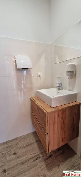 Fürdőszoba mosdóval és fa dekoros szekrénnyel a vendéglátóipari helyiségekben.