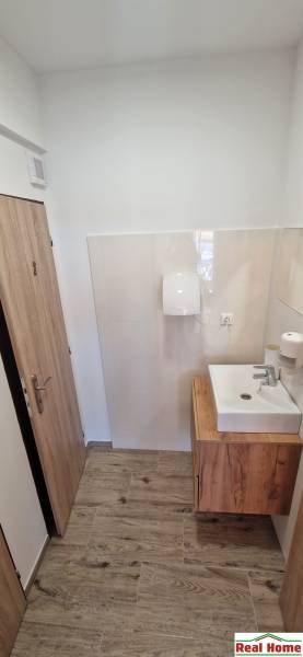 Fürdőszoba mosdóval és fa dekorációjú padlóval a gasztronómiai terekben.