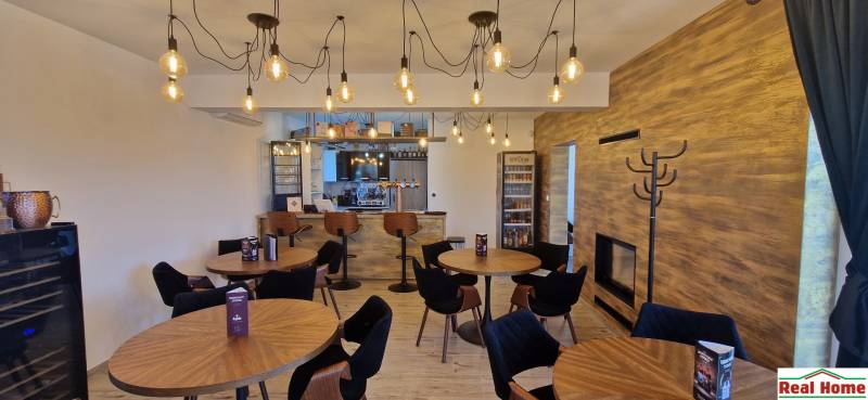 Vendéglátóhelyek fa mintázatú padlóval és függő lámpákkal.